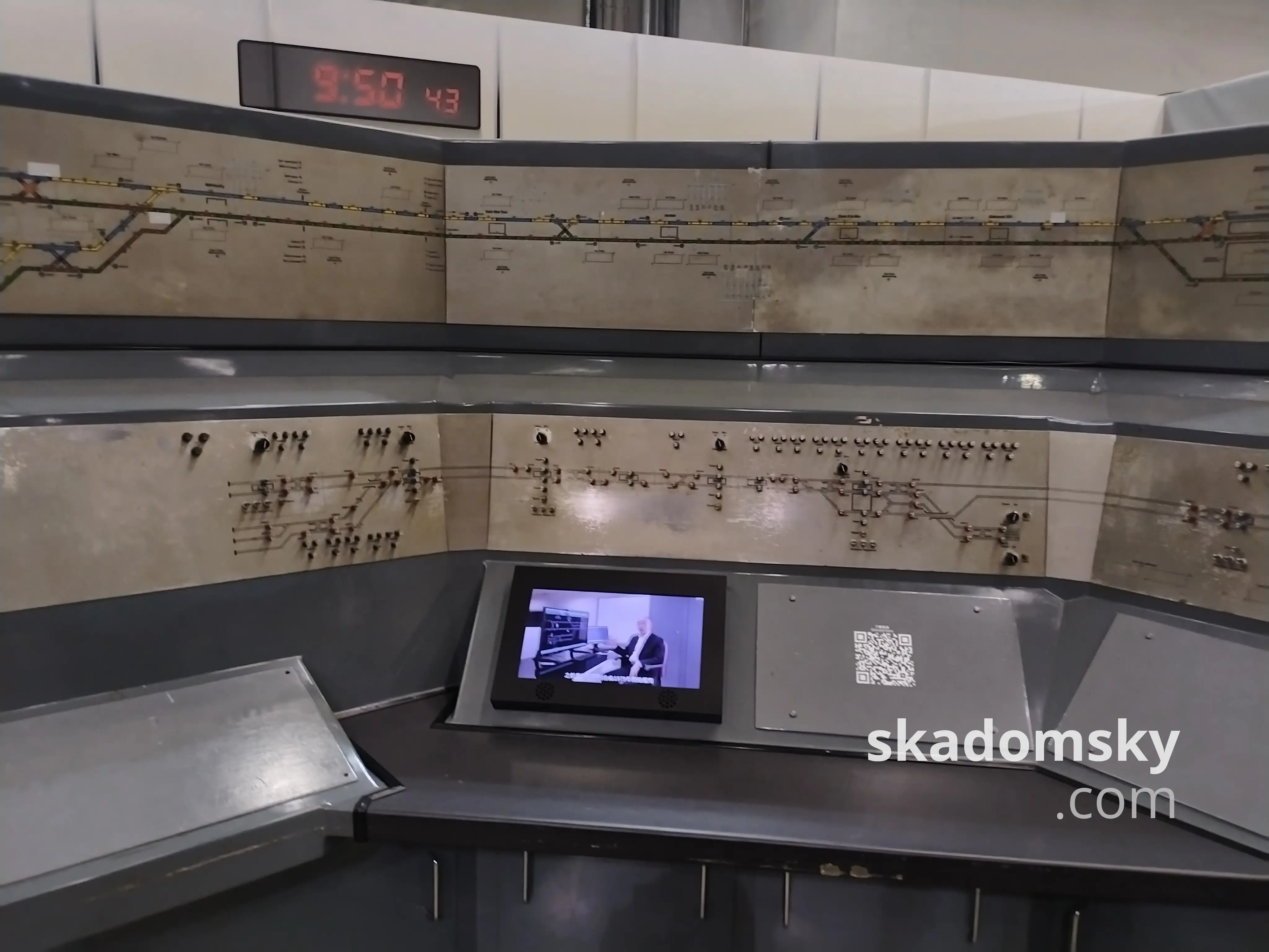 旧调车控制台。所有的交互界面都被遮挡,上方的电视播放着宣传影片。