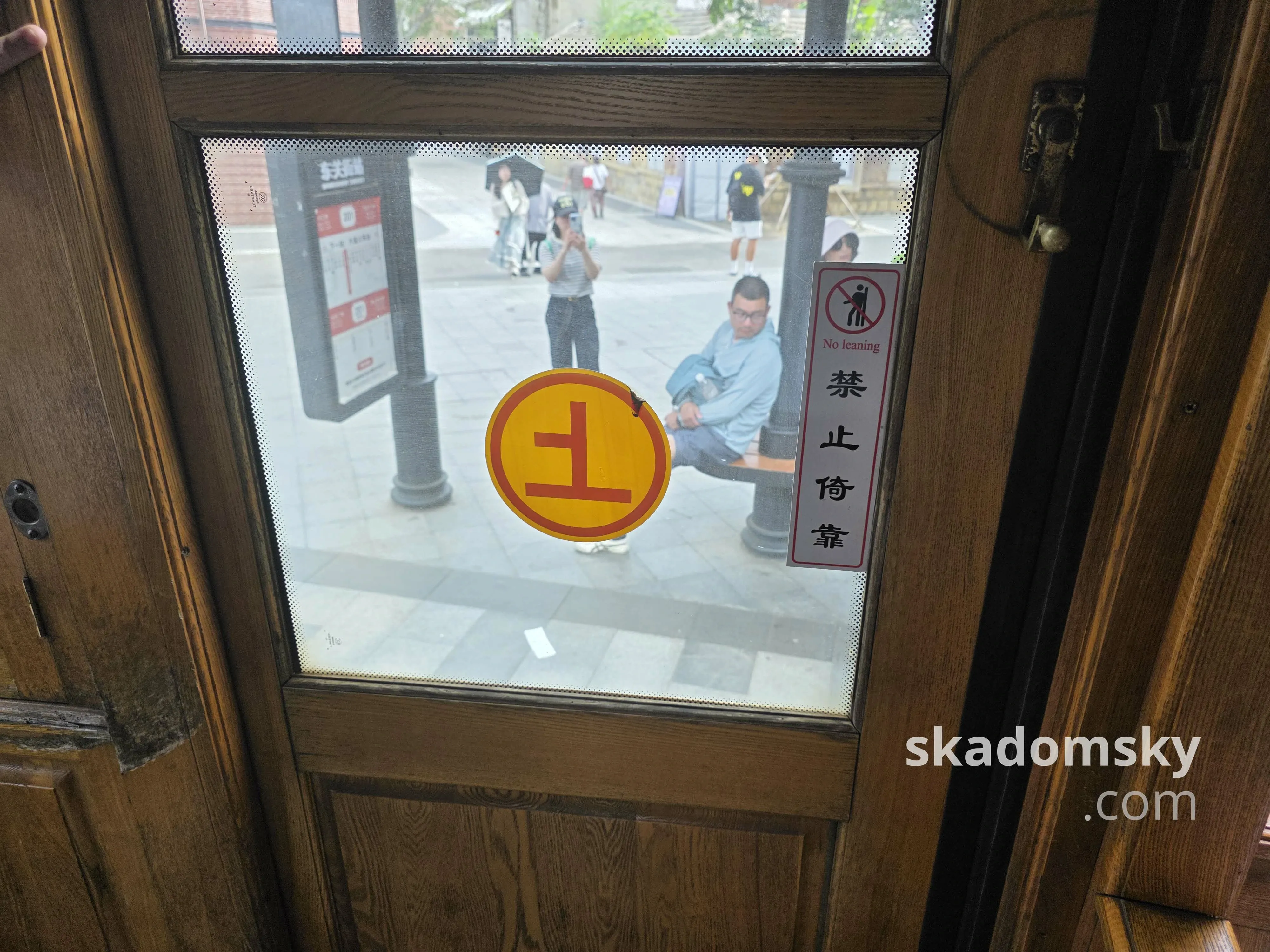 电车的木质上车车门，中间贴有“上”的字样，右边贴有“禁止倚靠”的警告。透过玻璃可以看到一旁的东关街站站台。