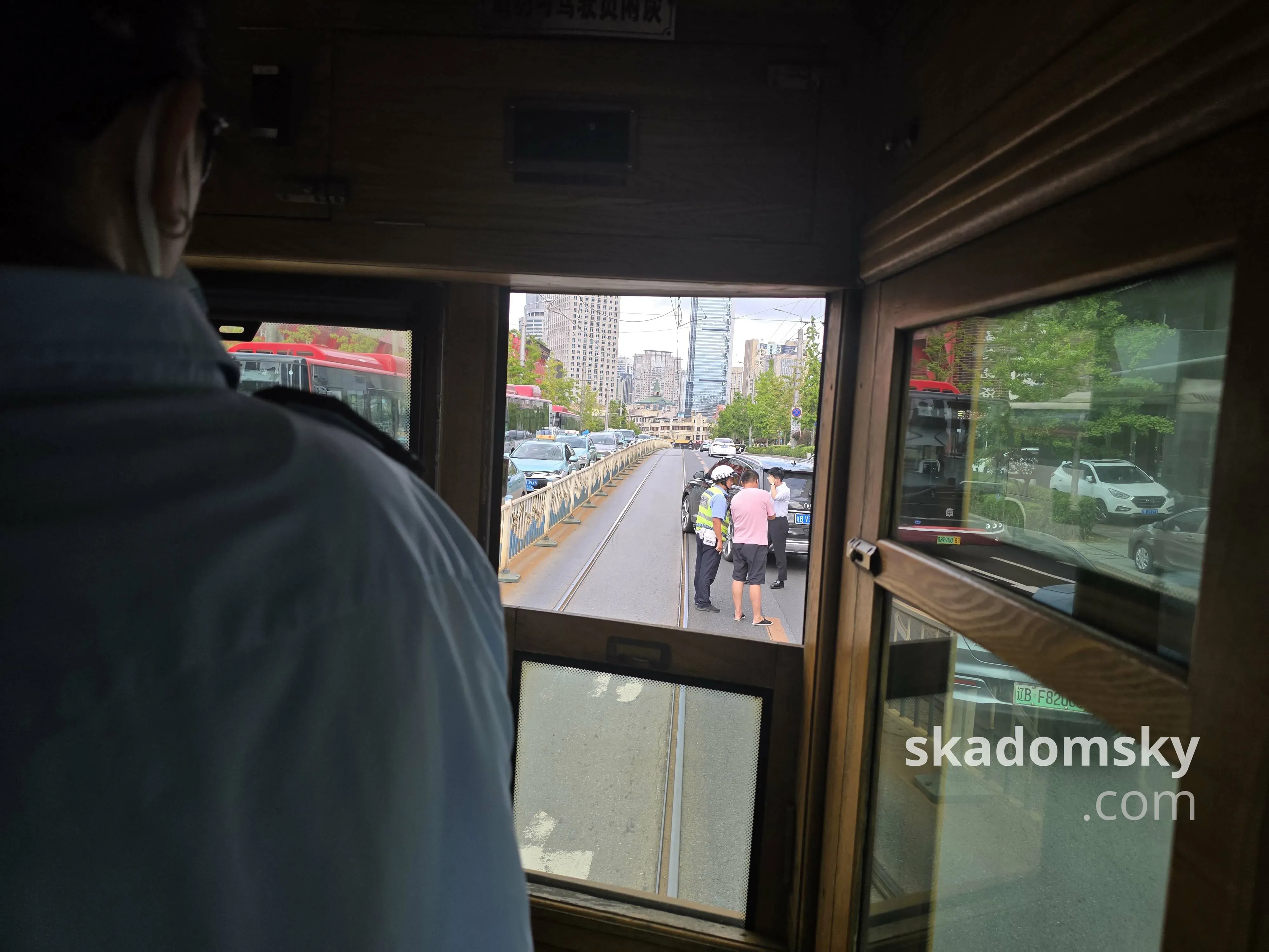 一辆黑色的SUV的前部挡住了有轨电车的轨道。交警正在跟两位穿着衬衫的男士交谈。