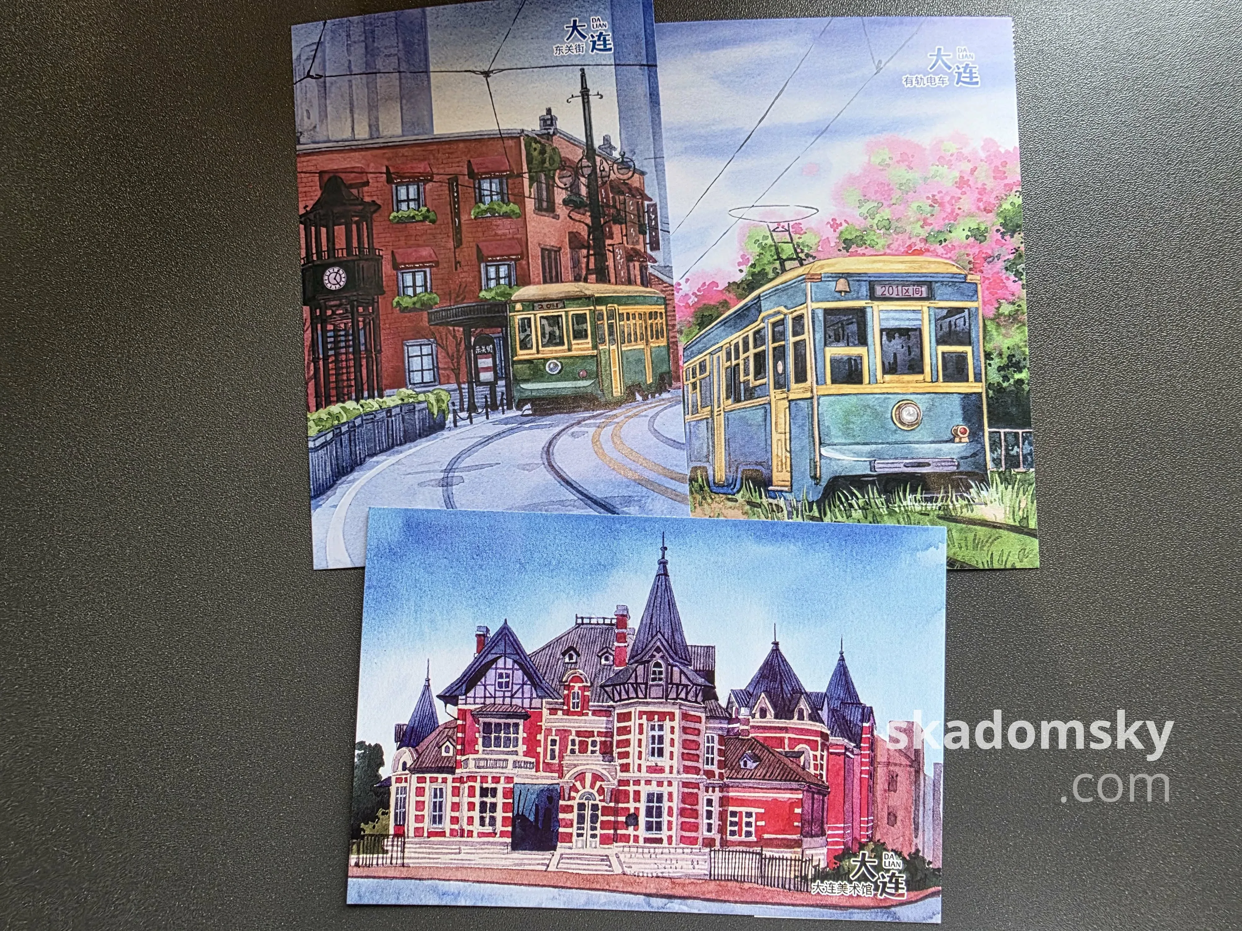 三张明信片。上面两张展示了大连的老式有轨电车，下面一张展示了大连美术馆外景。